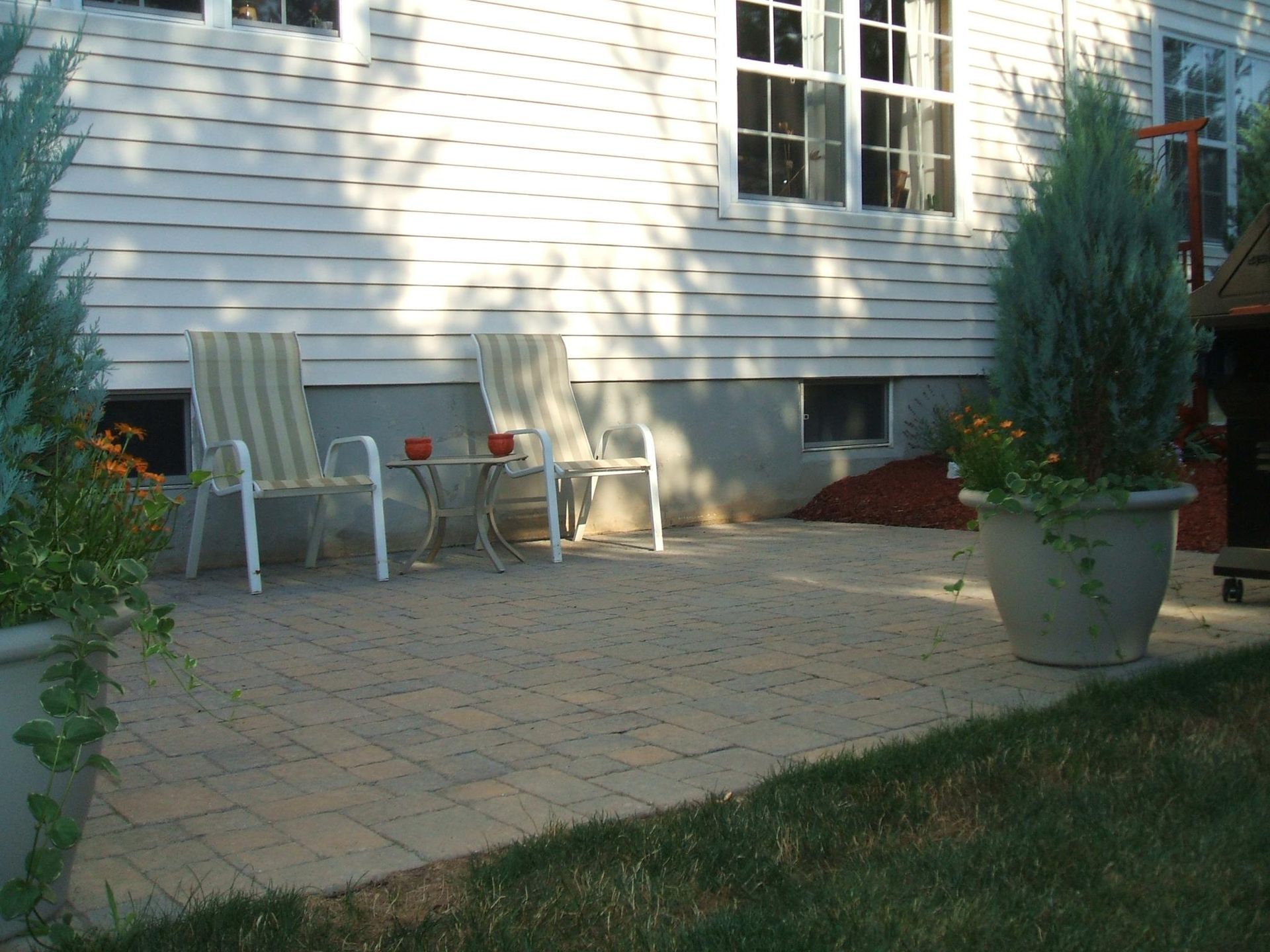 A patio with chairs and a table in front of a house