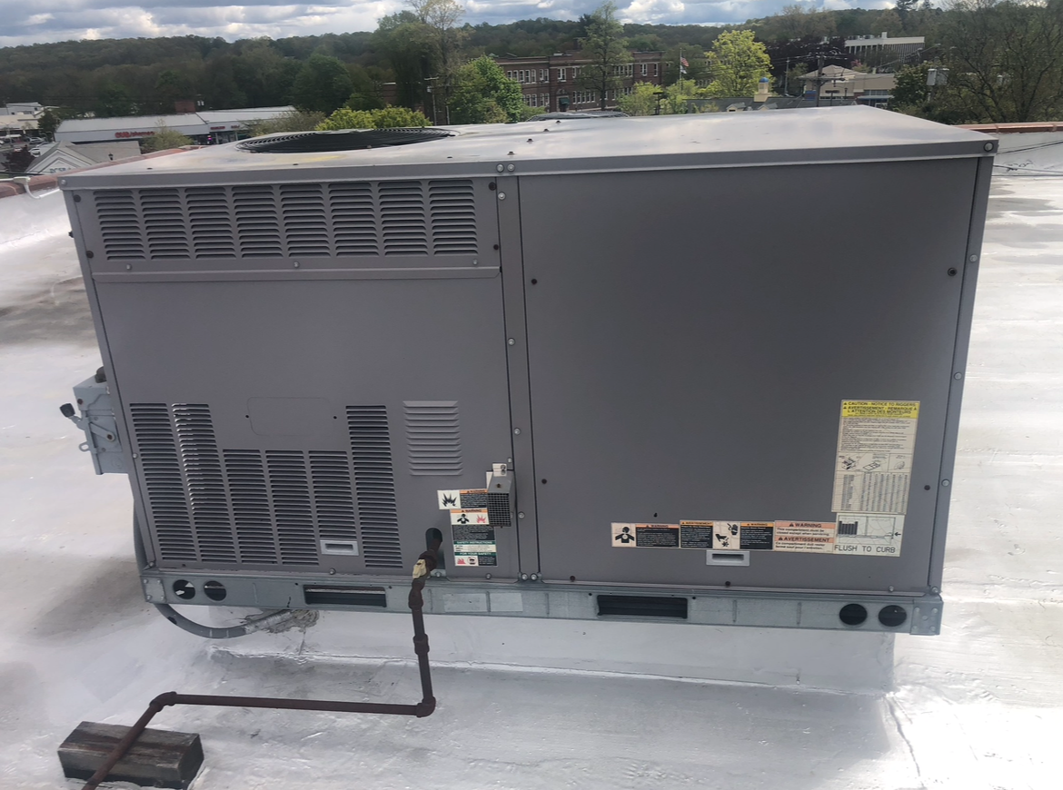 An air conditioner is sitting on top of a white roof.