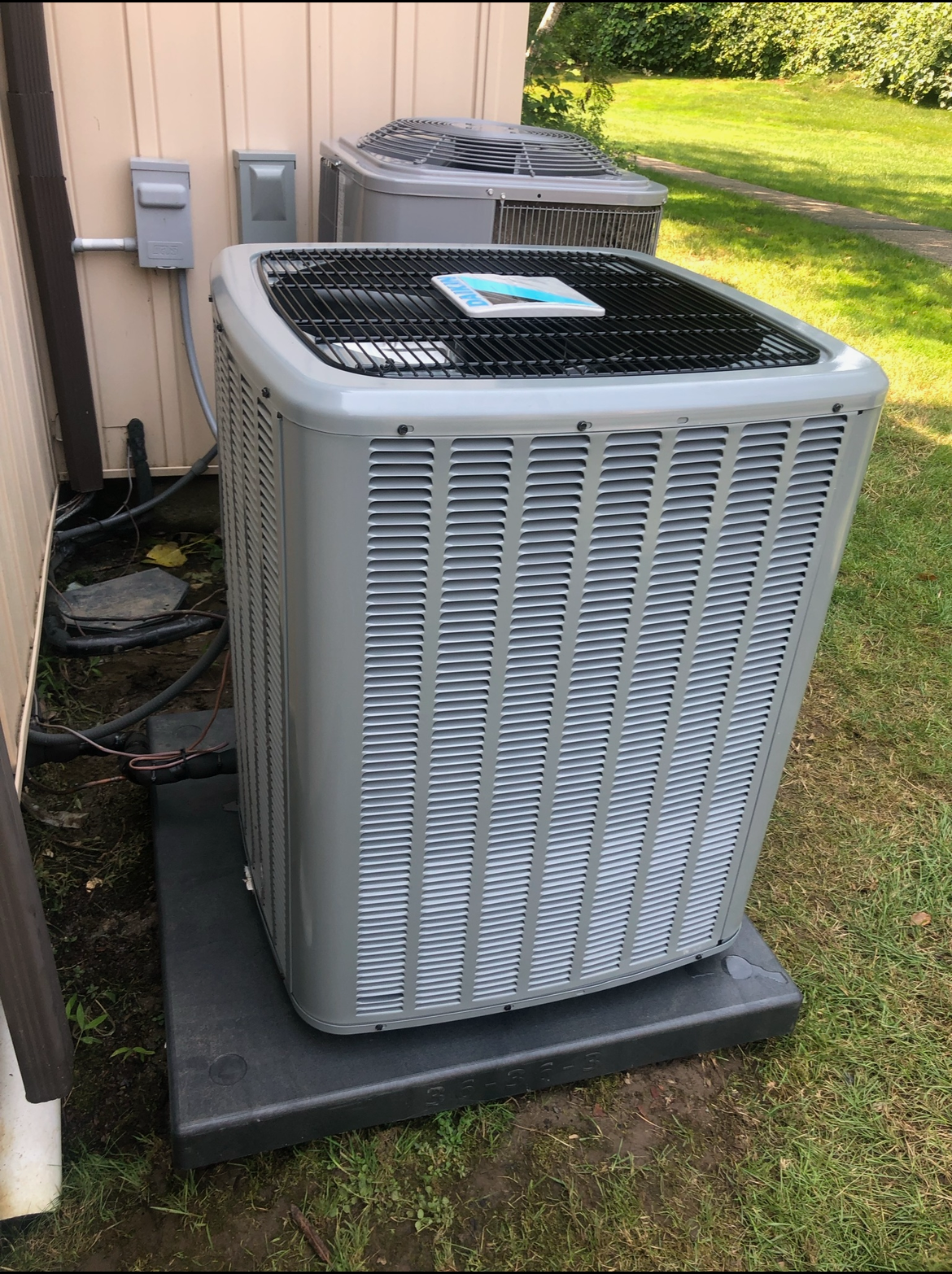 A large air conditioner is sitting outside of a house.