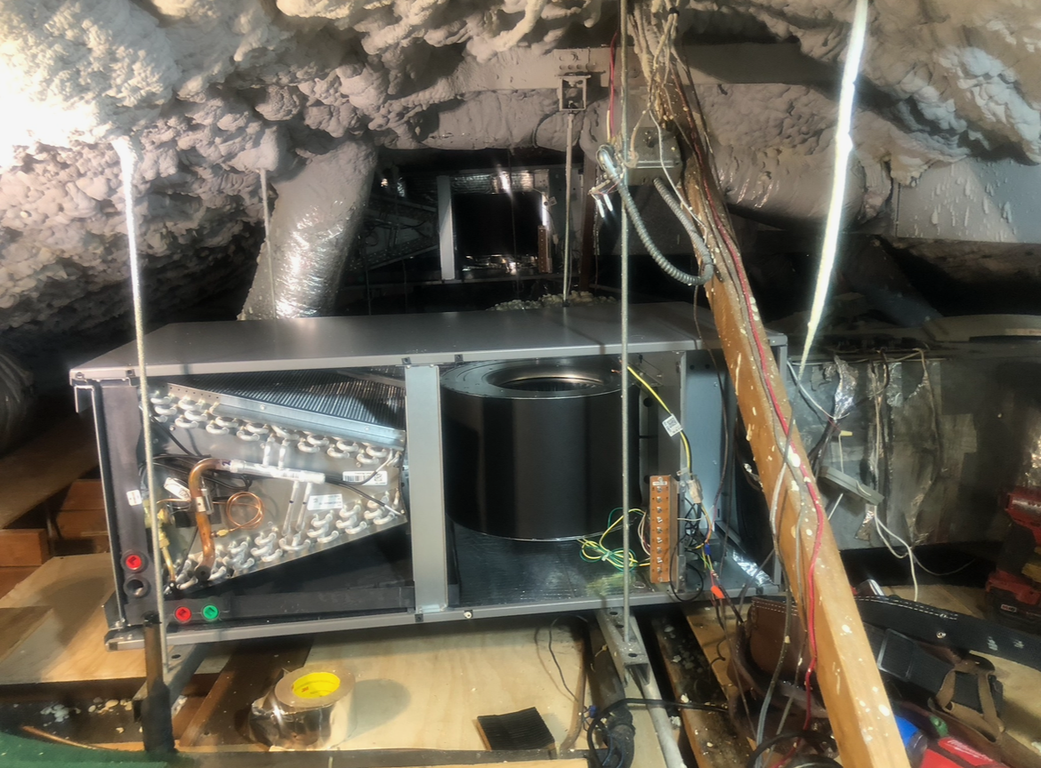 An air conditioner is sitting in the attic of a house.