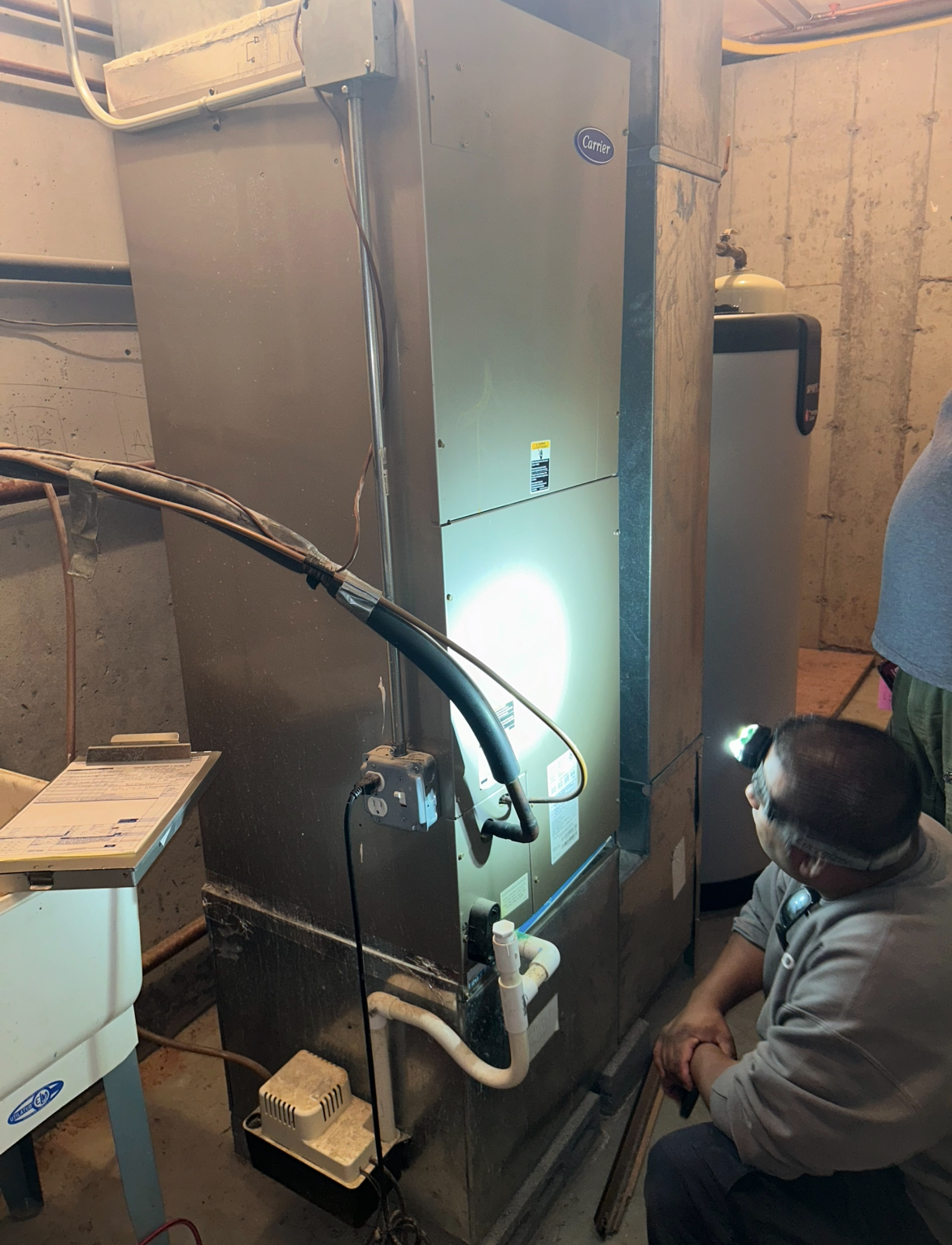 A man is kneeling down in front of a heater in a room.