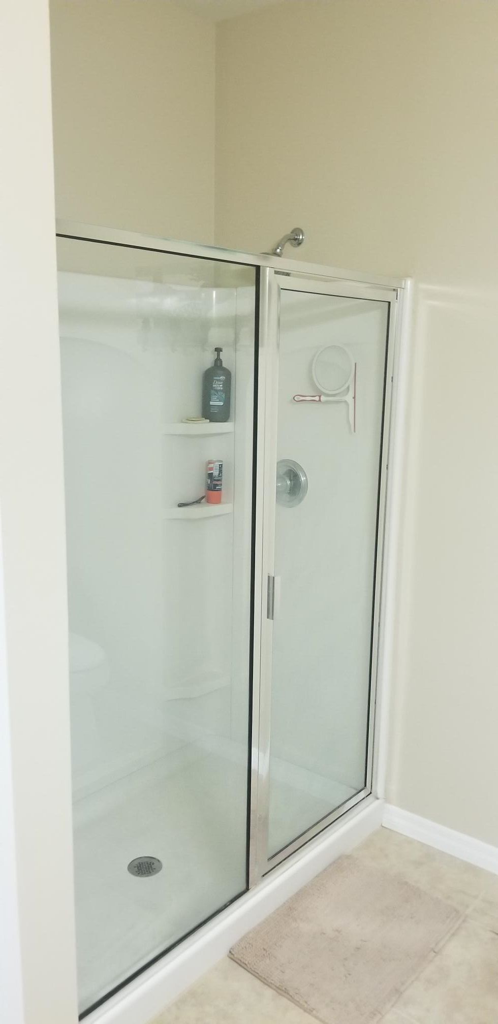 A bathroom with a walk in shower with a glass door.