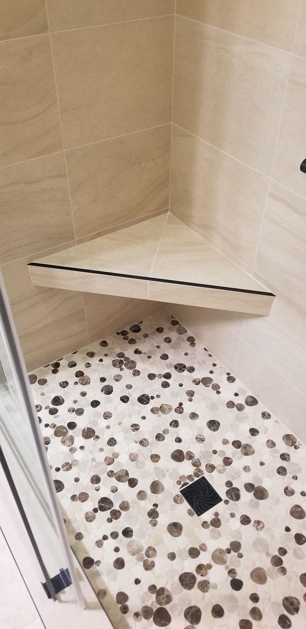 A shower with a corner shelf and a tiled floor.