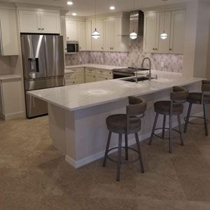A kitchen with white cabinets, stainless steel appliances, a large island, and stools.