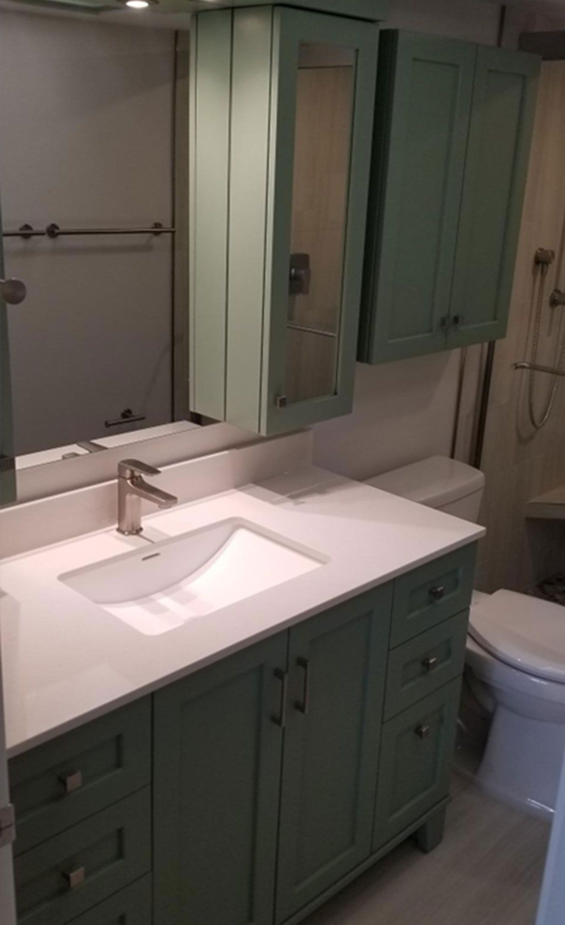 Green bathroom vanity and mirror cabinets with white countertop