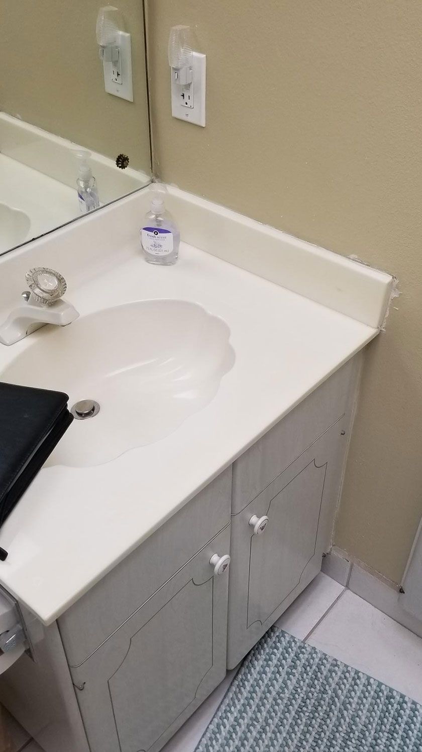 White bathroom sink on a white cabinet with a mirror and light switch