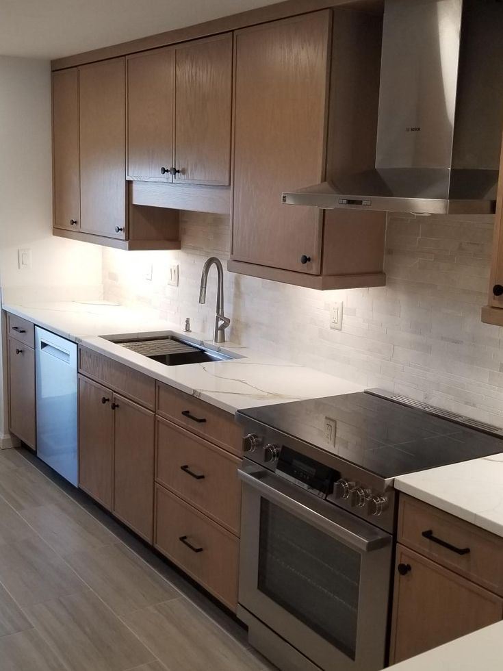 Modern kitchen with light brown cabinets, stainless steel appliances, and white countertops.