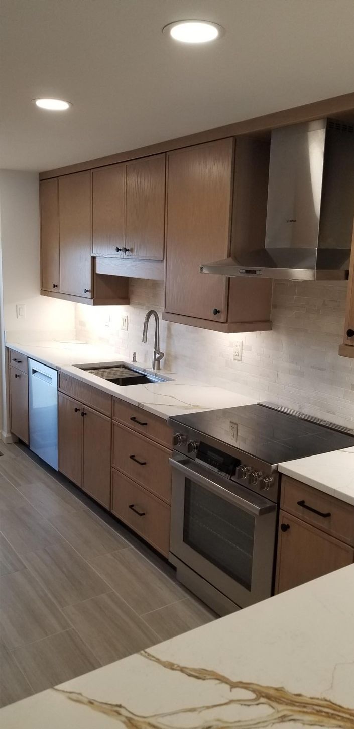 Modern kitchen with light brown cabinets, stainless steel appliances, and white countertops.