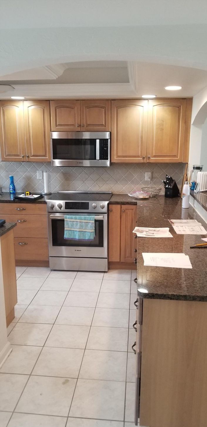 Kitchen with light wood cabinets, stainless steel appliances, and dark granite countertops.