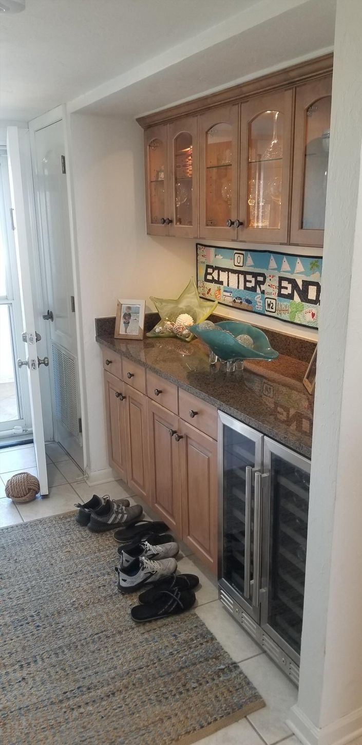 A cozy nook with wooden cabinets and a granite countertop holding decorative starfish and glassware.