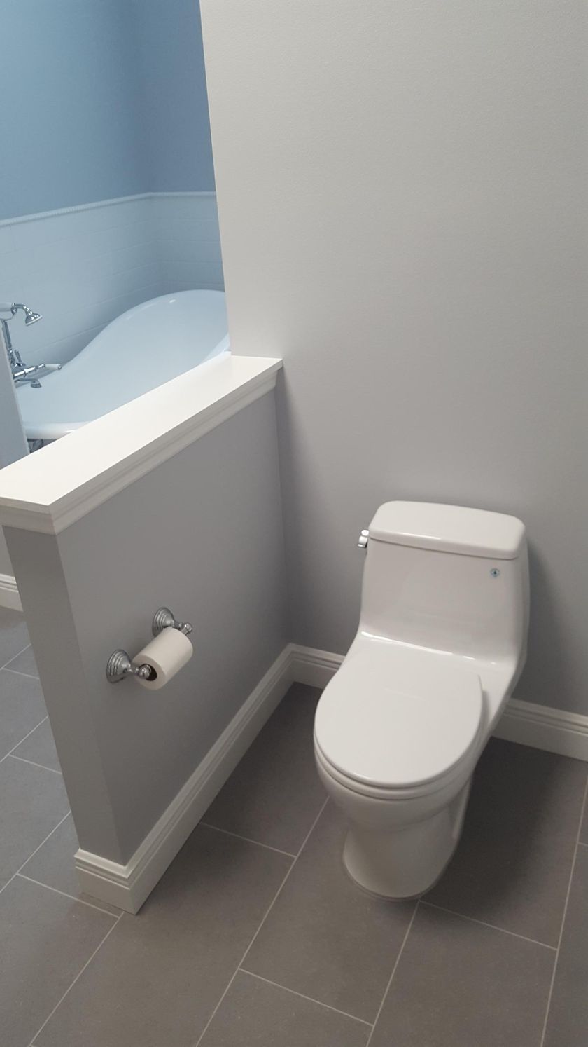 A toilet in a bathroom next to a bathtub