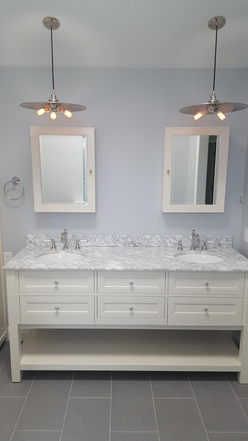 A bathroom with two sinks, two mirrors and a ceiling fan