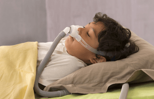 A boy on the bed with respiratory equipment