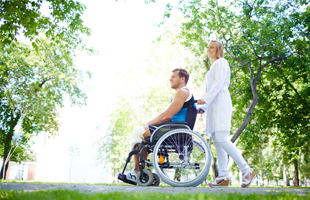 Lady pushing her husband on a wheel chair
