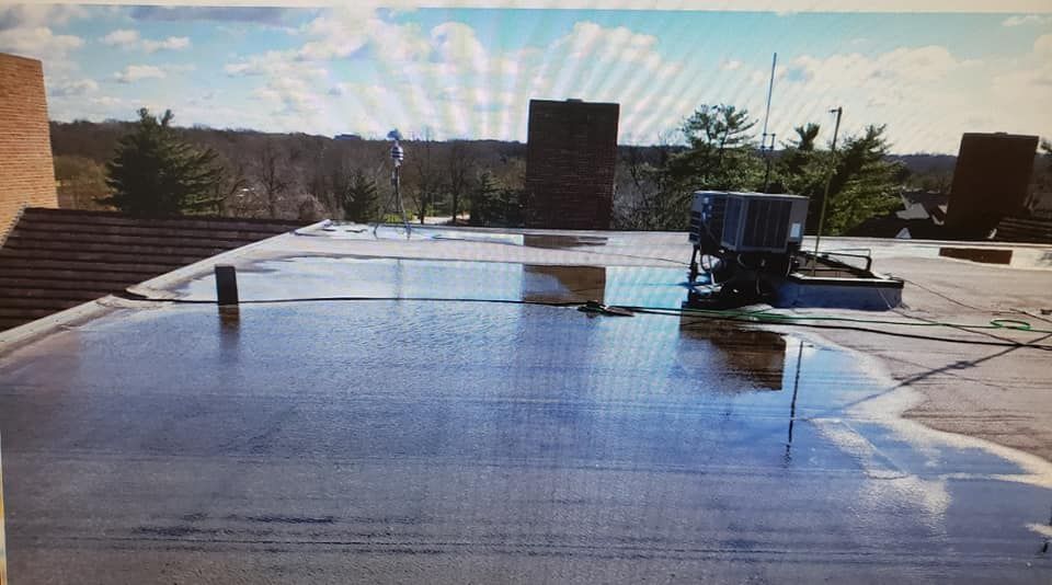 A flat commercial rooftop shows significant standing water around an HVAC unit on a sunny day.