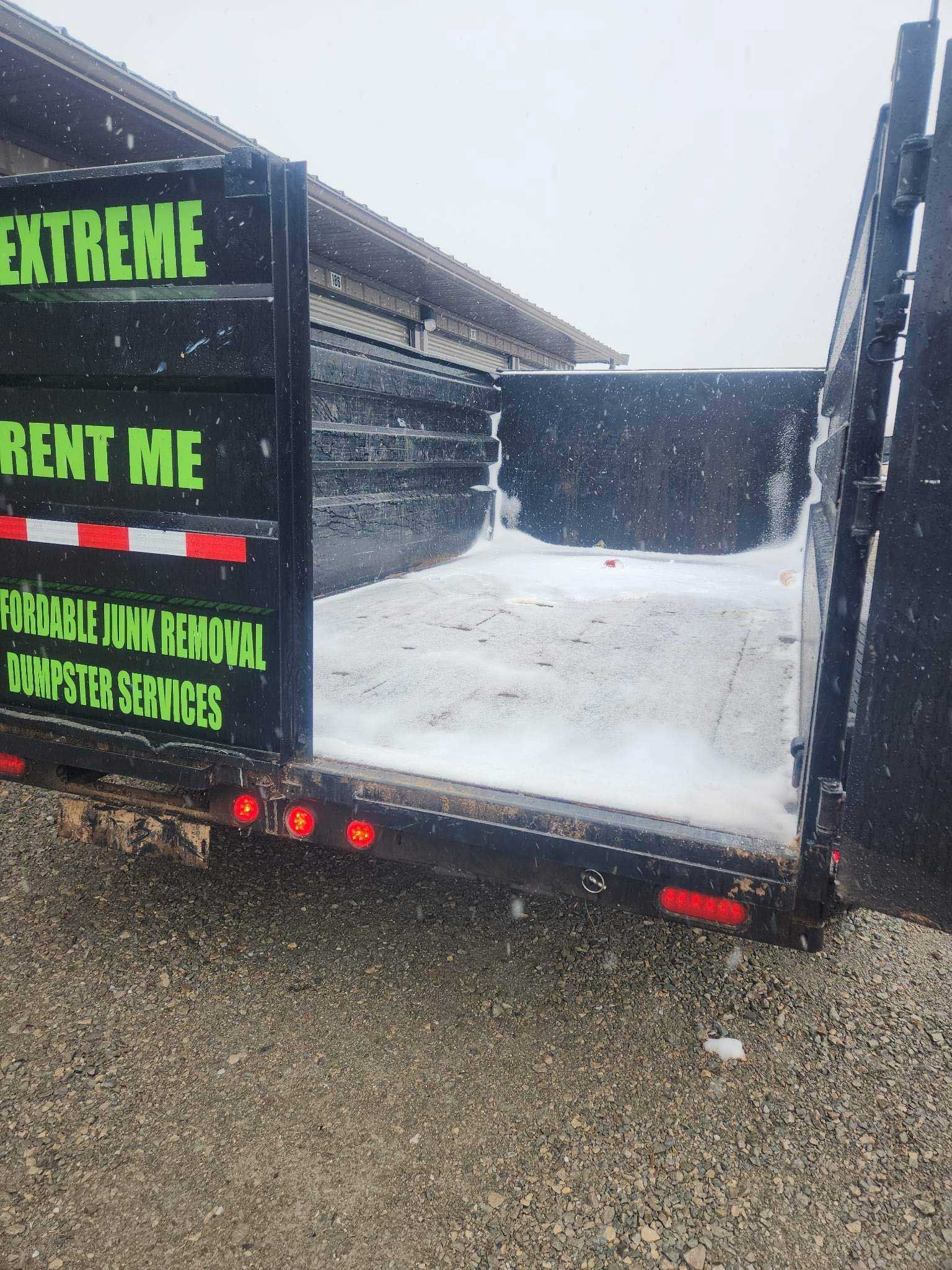 A black dump trailer with green text reading 