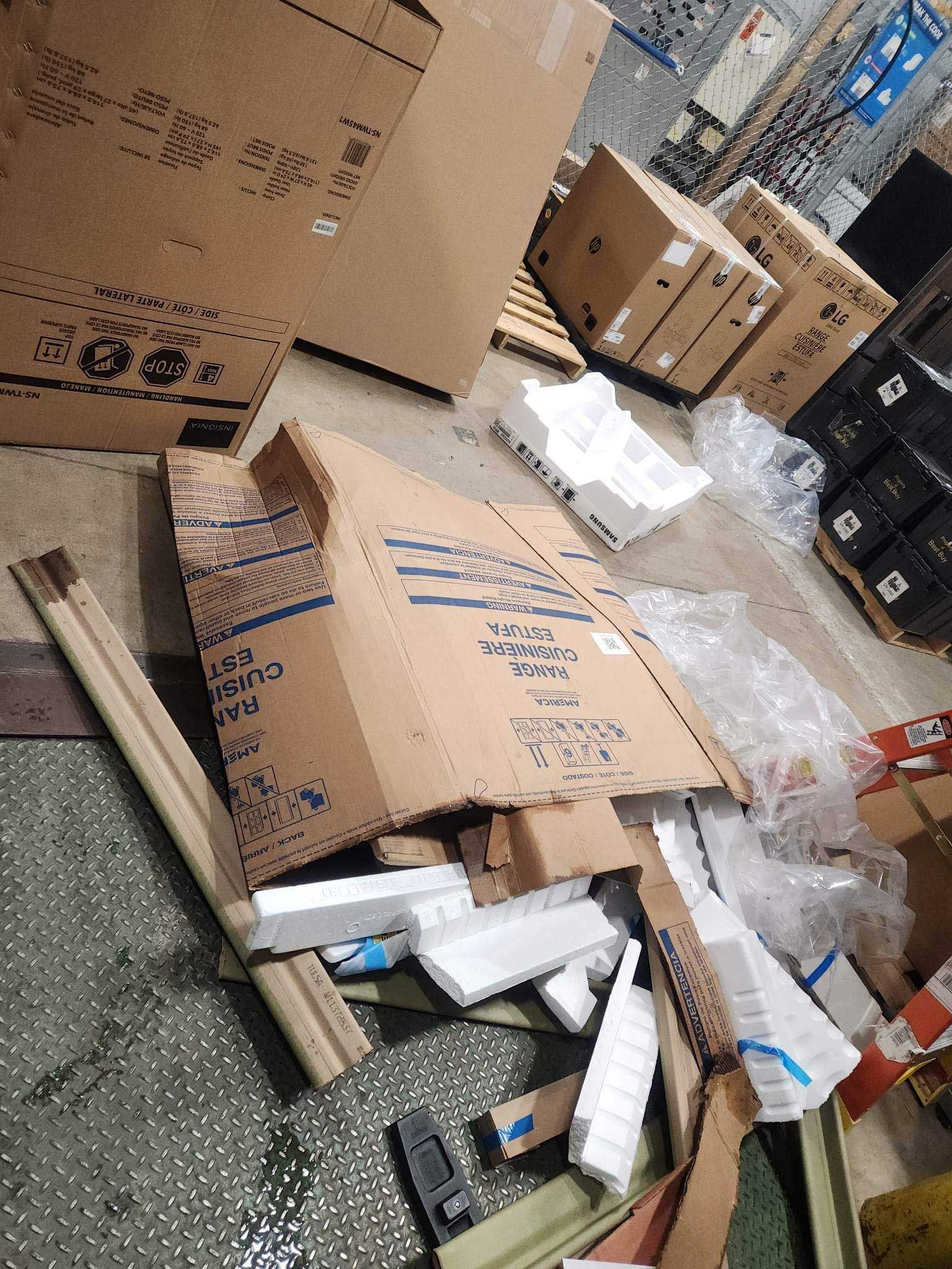 Cardboard boxes and discarded white styrofoam packaging material scattered on a warehouse floor.