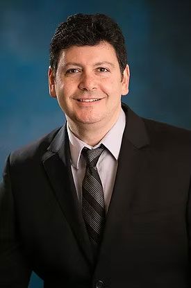 A man in a suit and tie is smiling for the camera.