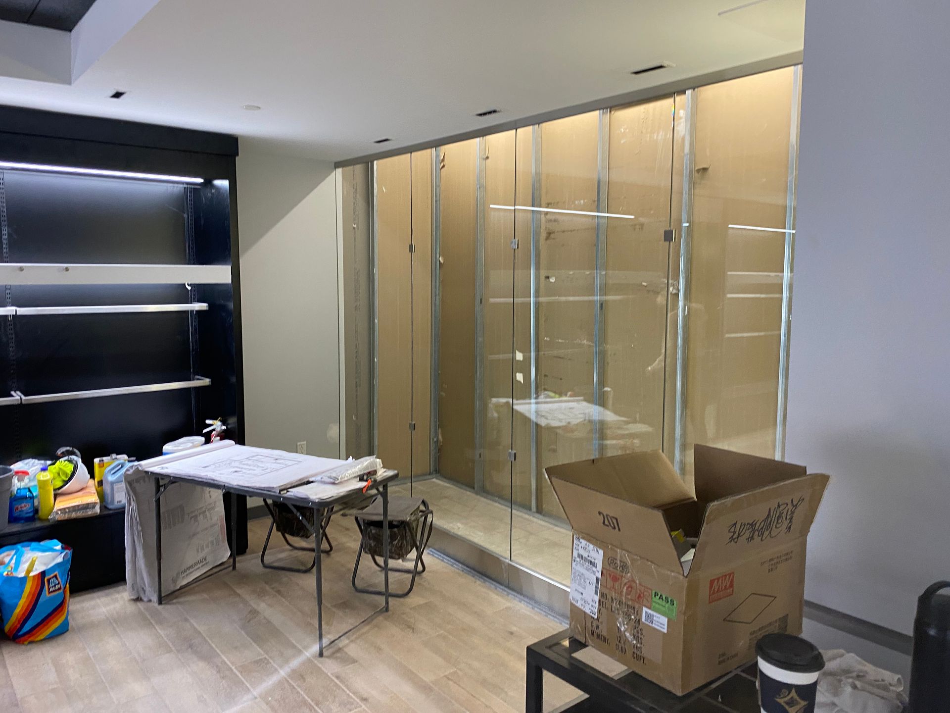 Interior space with construction in progress. Drywall, metal studs, boxes, and table present.