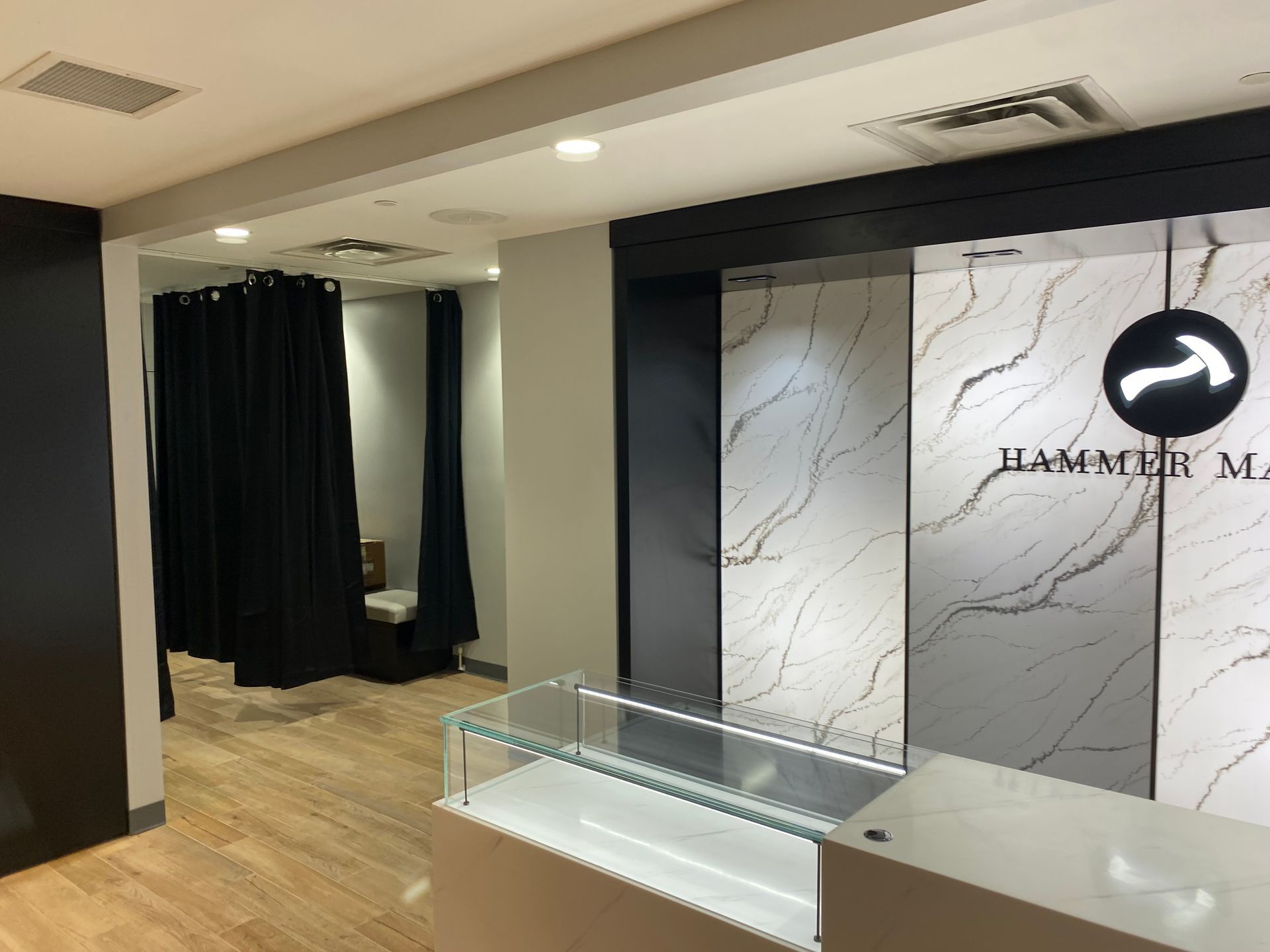 Interior showroom with stone slabs on display; a check-in area; and fitting rooms with black curtains.