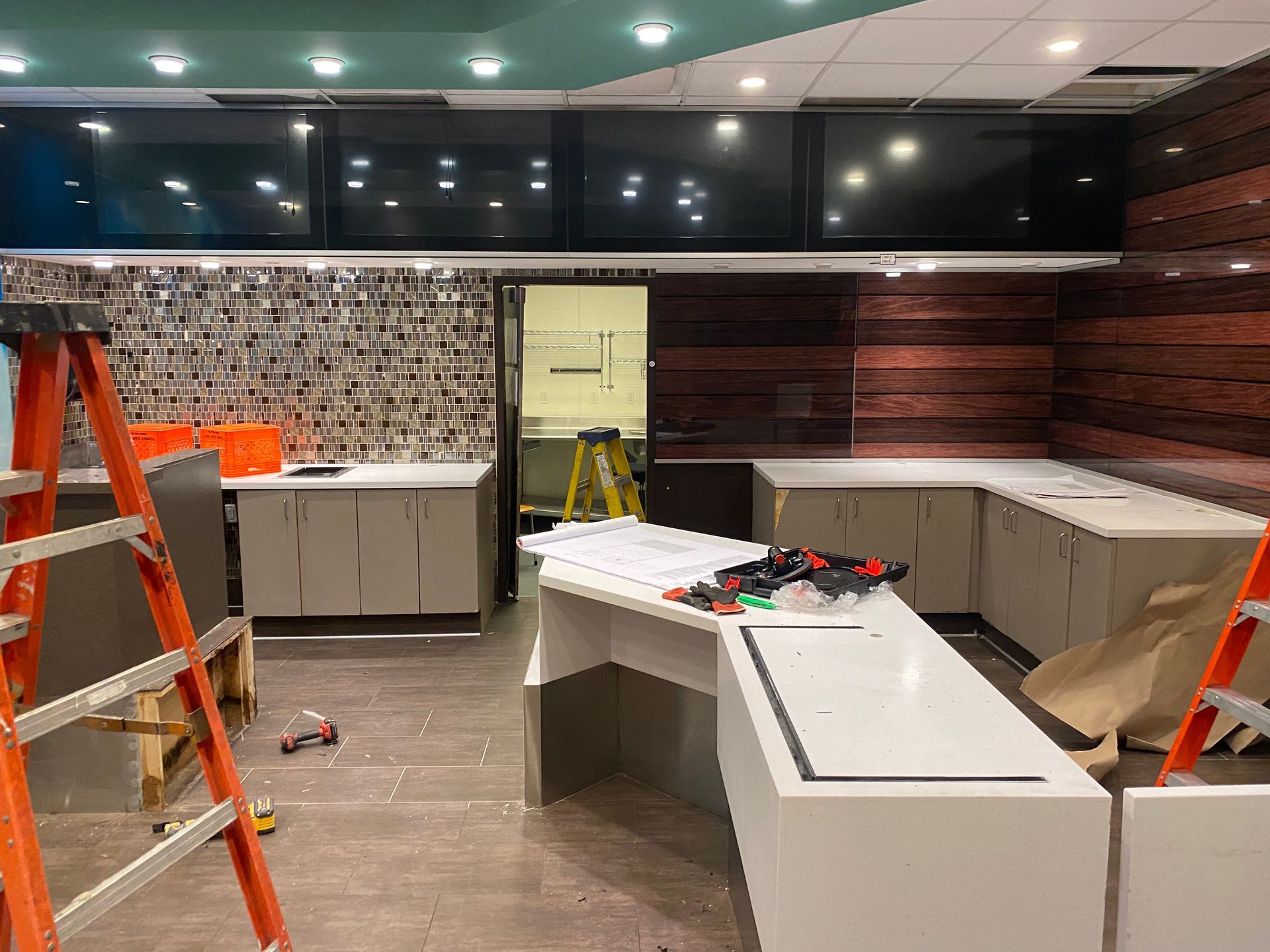 Interior view of a commercial space under construction. Cabinets, screens, and tools are visible.