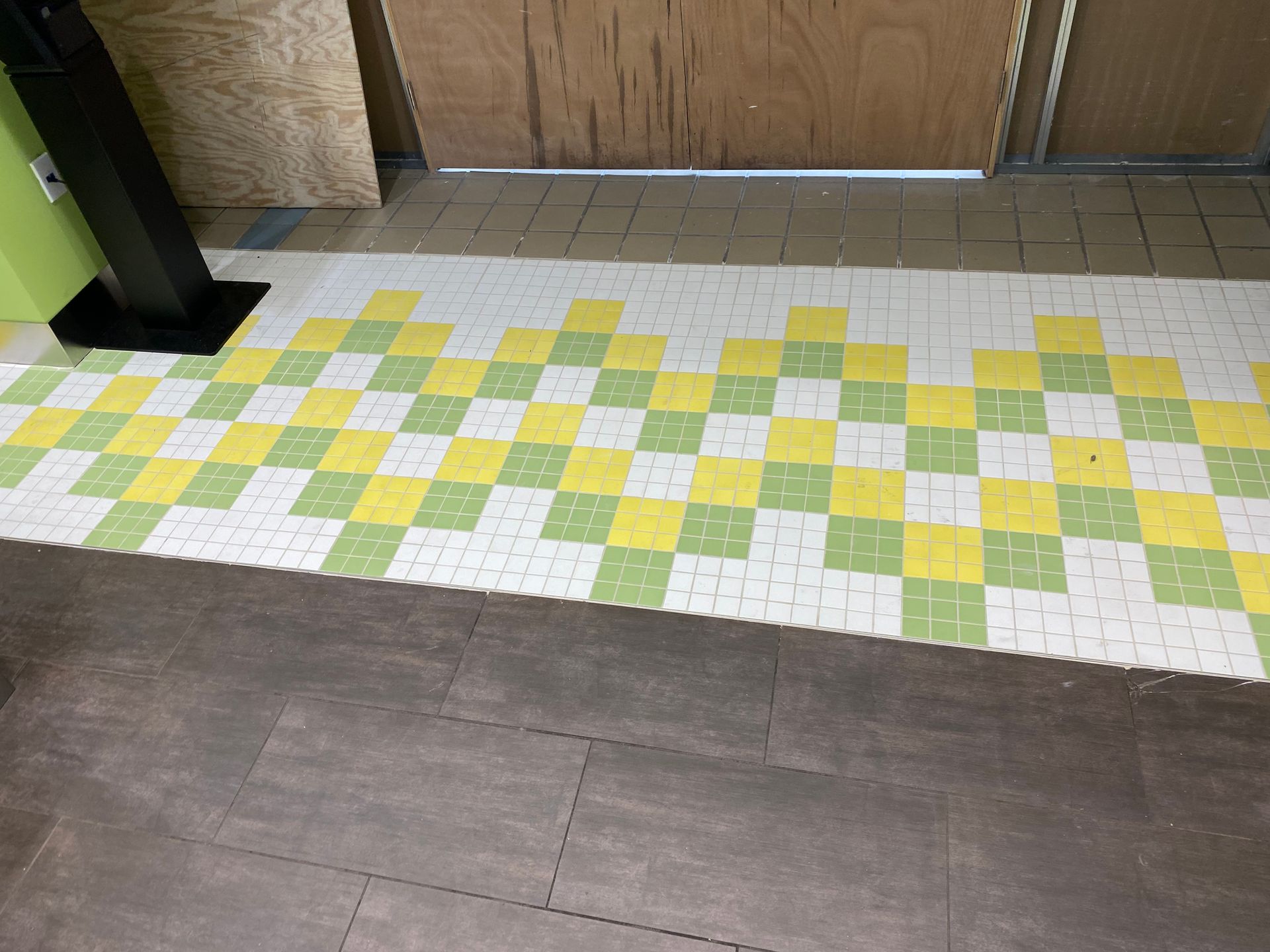Checkered tile floor in green, yellow, and white, with a dark gray floor bordering it.