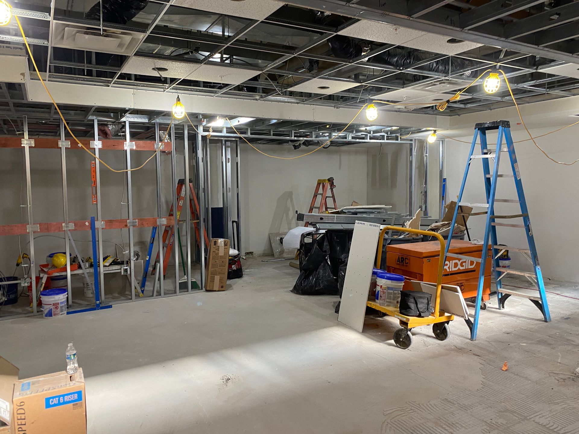 Construction site interior; metal framework, ladders, exposed ceiling, and tools.