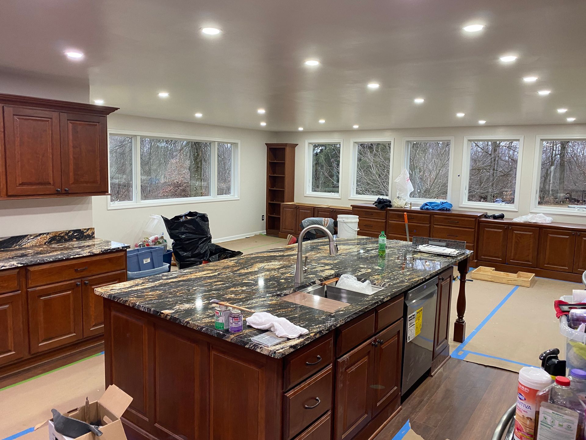 Kitchen with dark cabinets, granite countertops, and island; windows overlook trees.