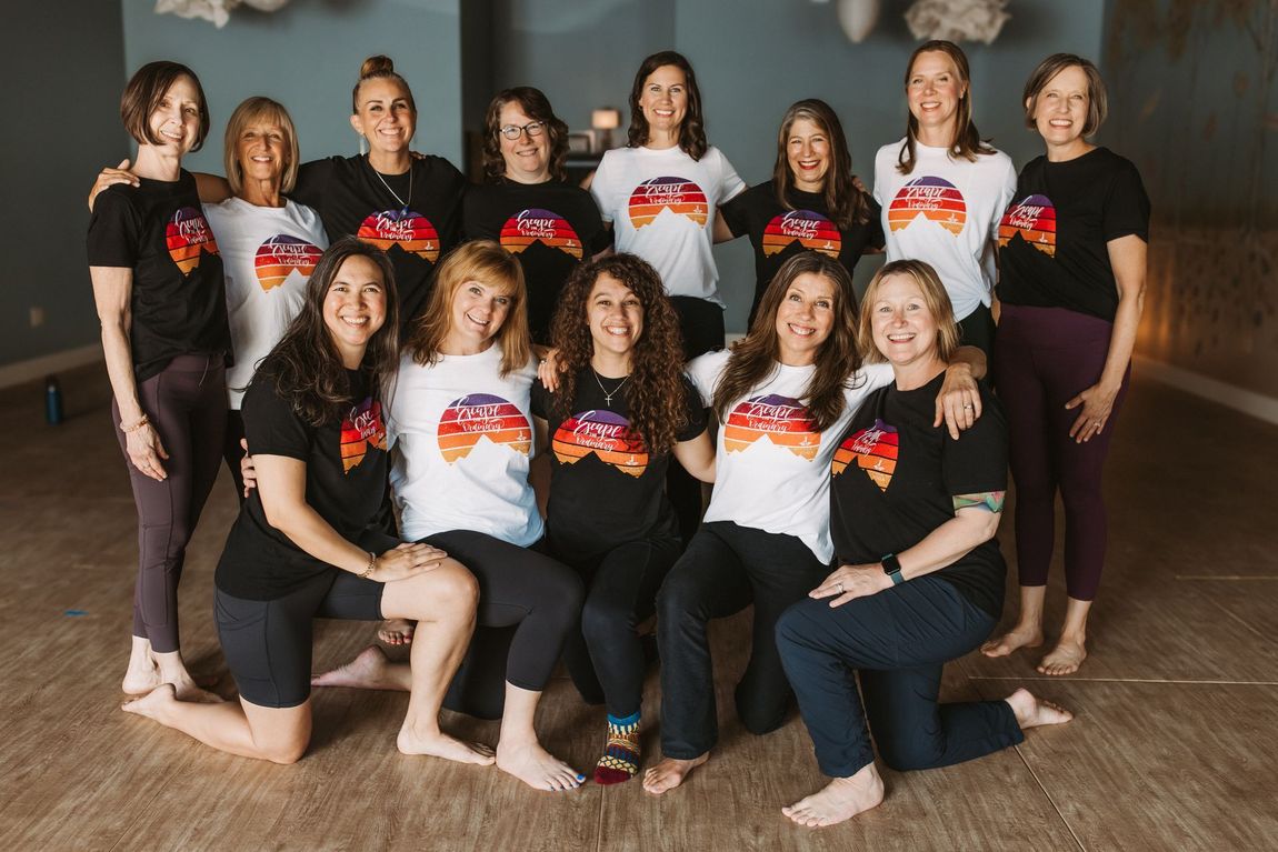 A group of people wearing matching shirts with a mountain graphic pose together in a studio.