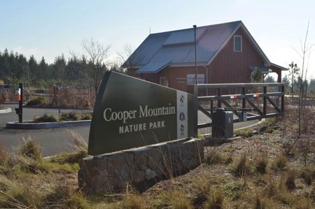 Cooper Mountain Nature Park entrance sign, brown building in background.