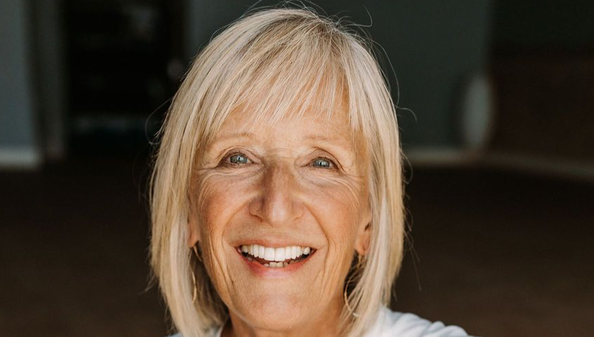 Smiling blonde woman in a white shirt against a dark background