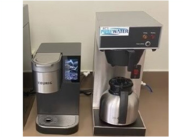 Two coffee makers are sitting next to each other on a table.