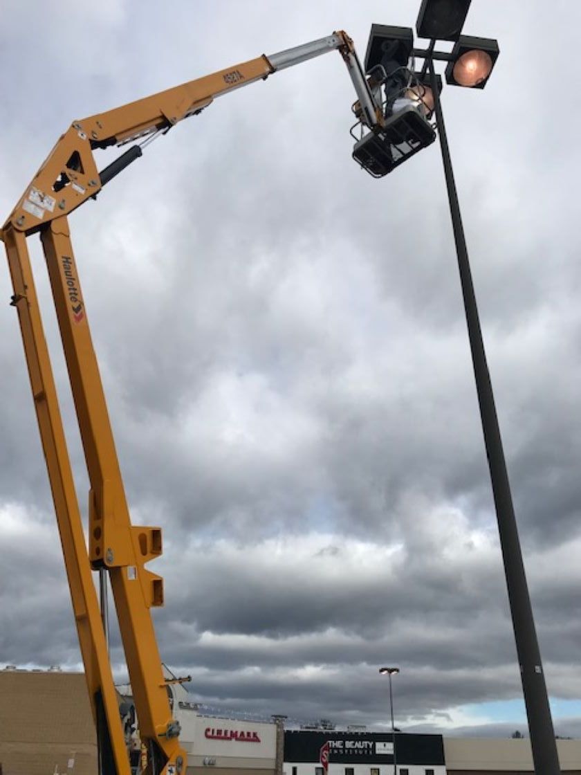a yellow crane is working on a street light
