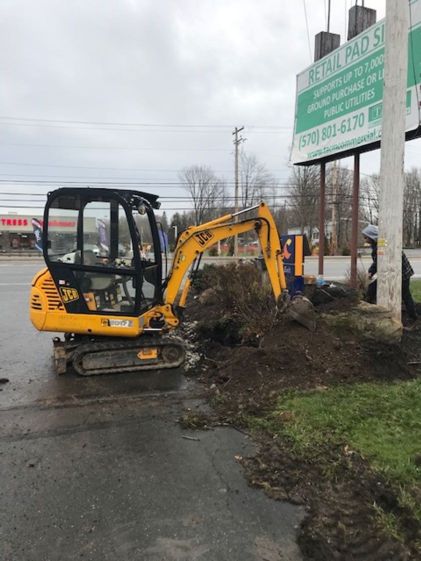 a small yellow excavator is digging a hole in the ground .