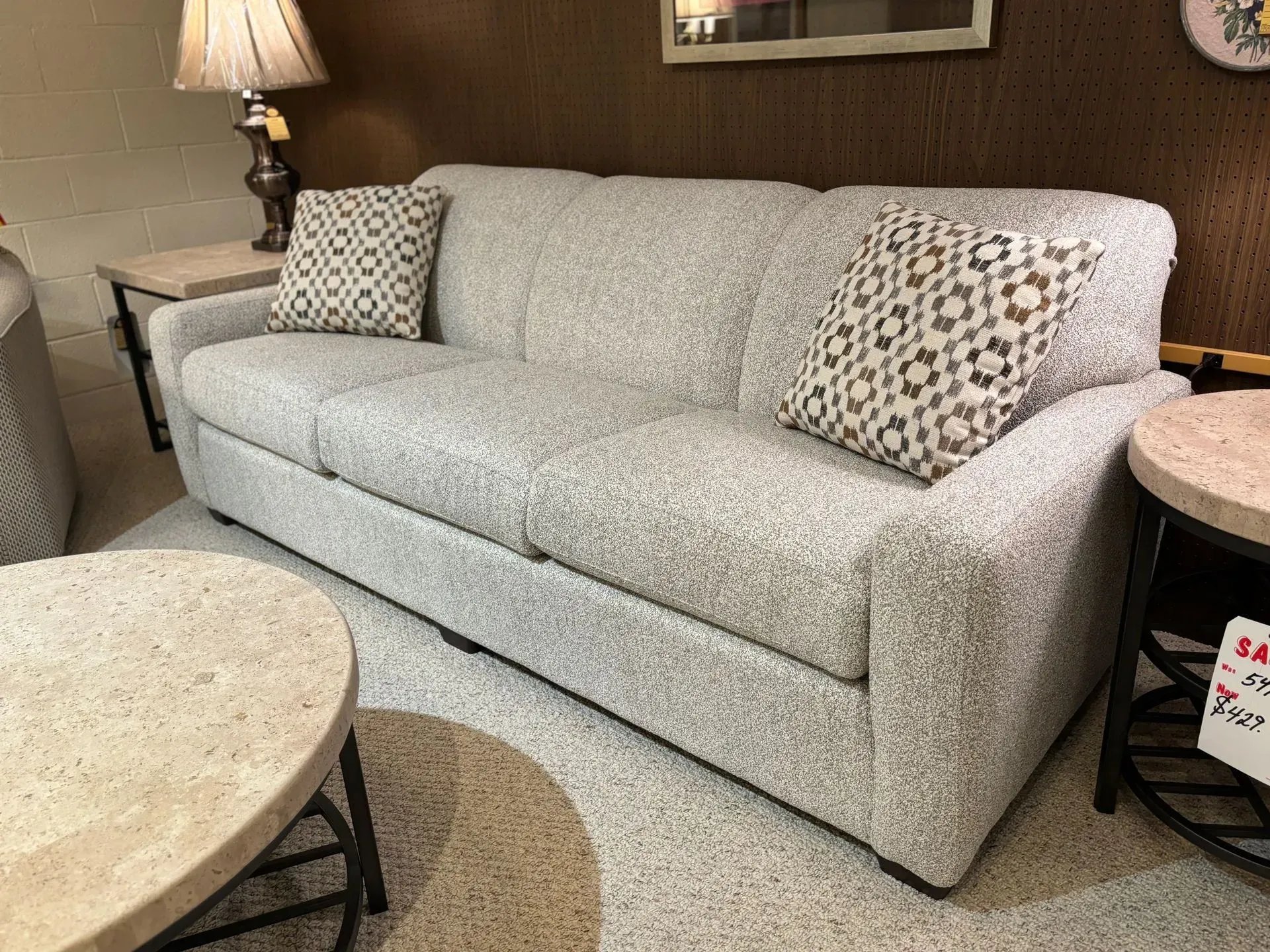 Gray upholstered sofa with patterned throw pillows in a furniture showroom.