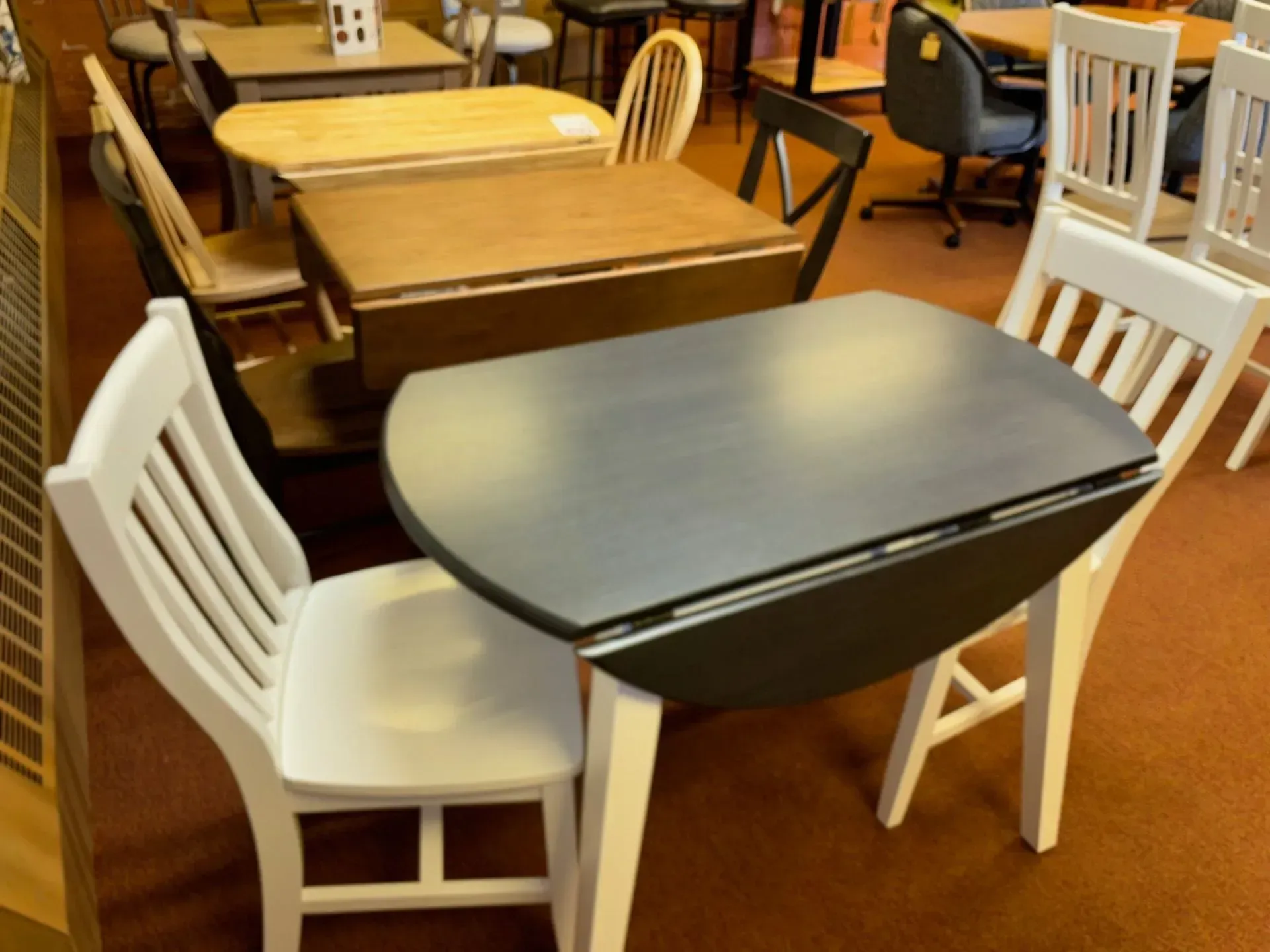A display of various small wooden tables and chairs in a store.