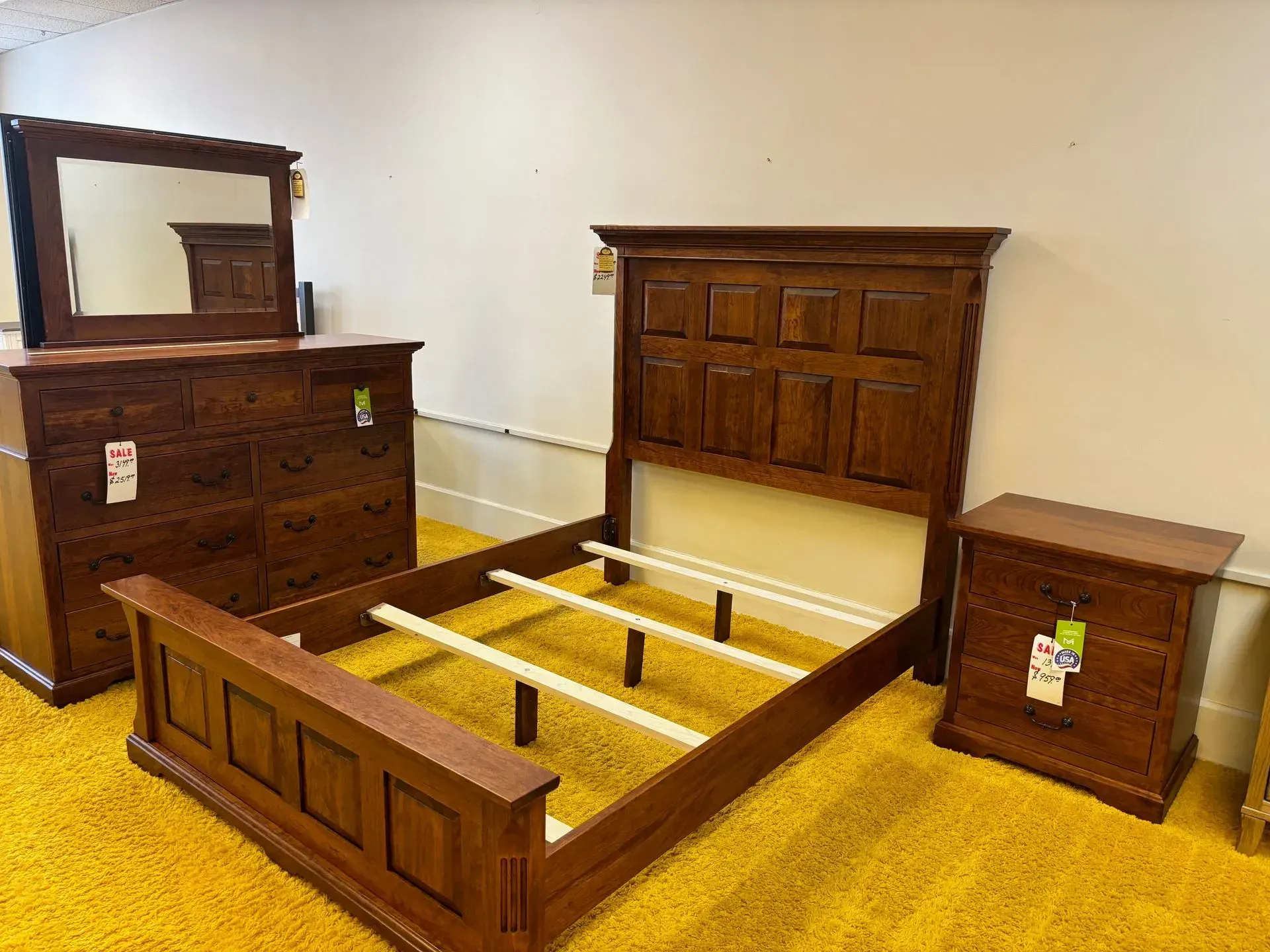 Bedroom furniture set: bed frame, dresser, mirror, nightstand. Brown wood, yellow carpet.