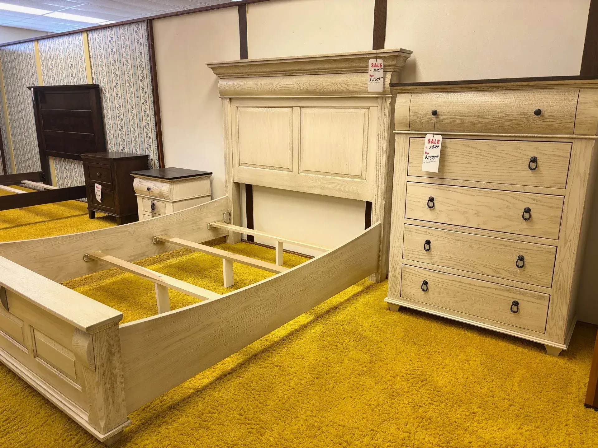 Bedroom set in off-white with distressed finish: bed frame, headboard, and chest of drawers, on yellow carpet.