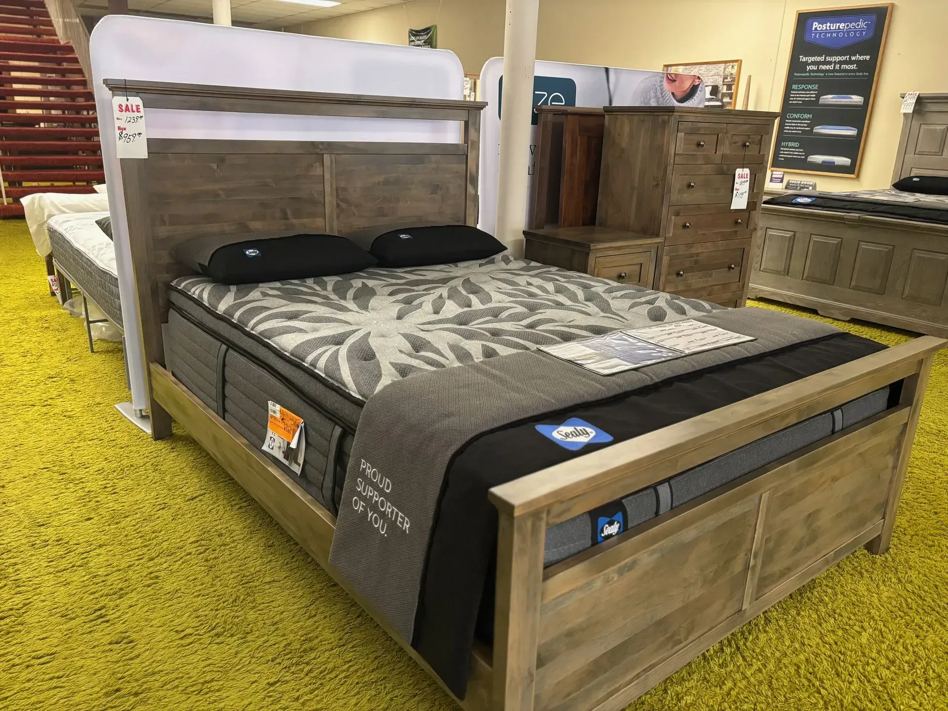 Wooden bed frame with mattress and pillows on display in a furniture store.