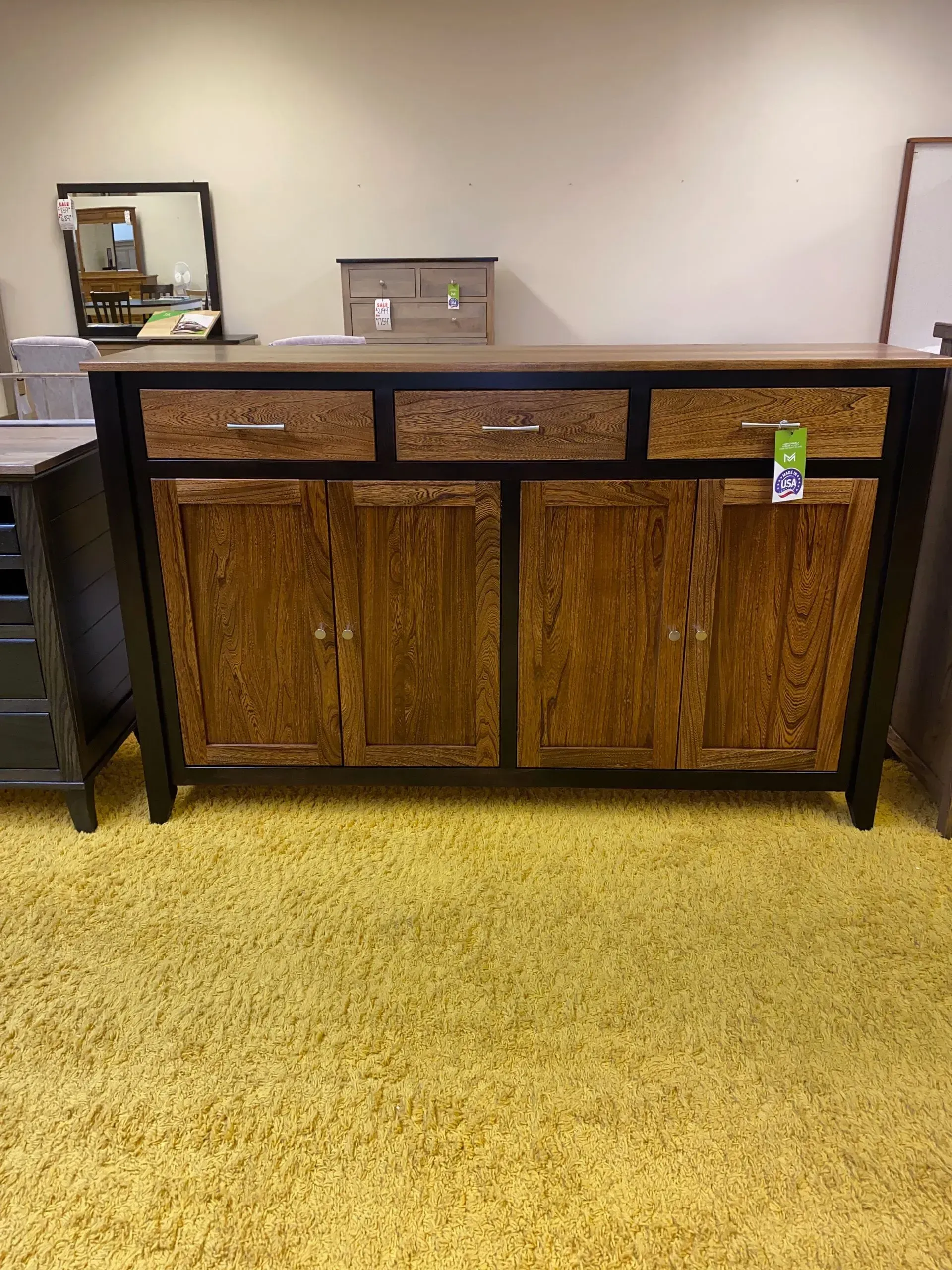 Wooden cabinet with three drawers and two doors, black trim, and yellow rug.