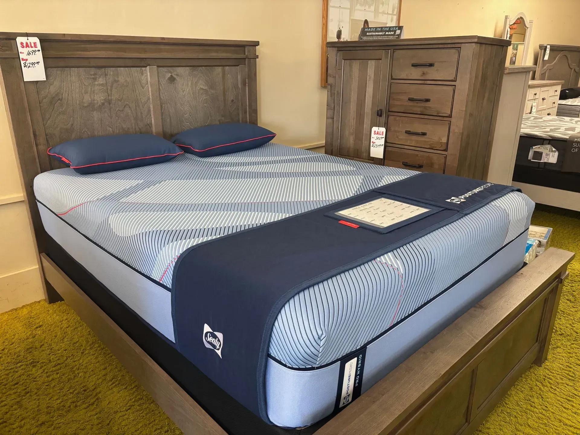 A bed with a blue and white striped mattress and a wooden headboard, with a matching dresser next to it.