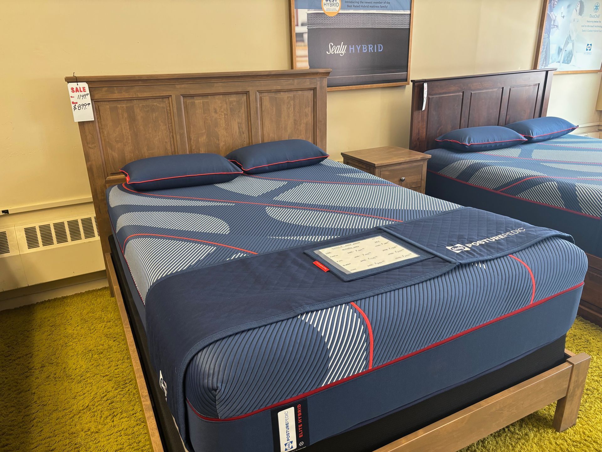 Two beds with blue mattresses and wooden headboards in a furniture store.