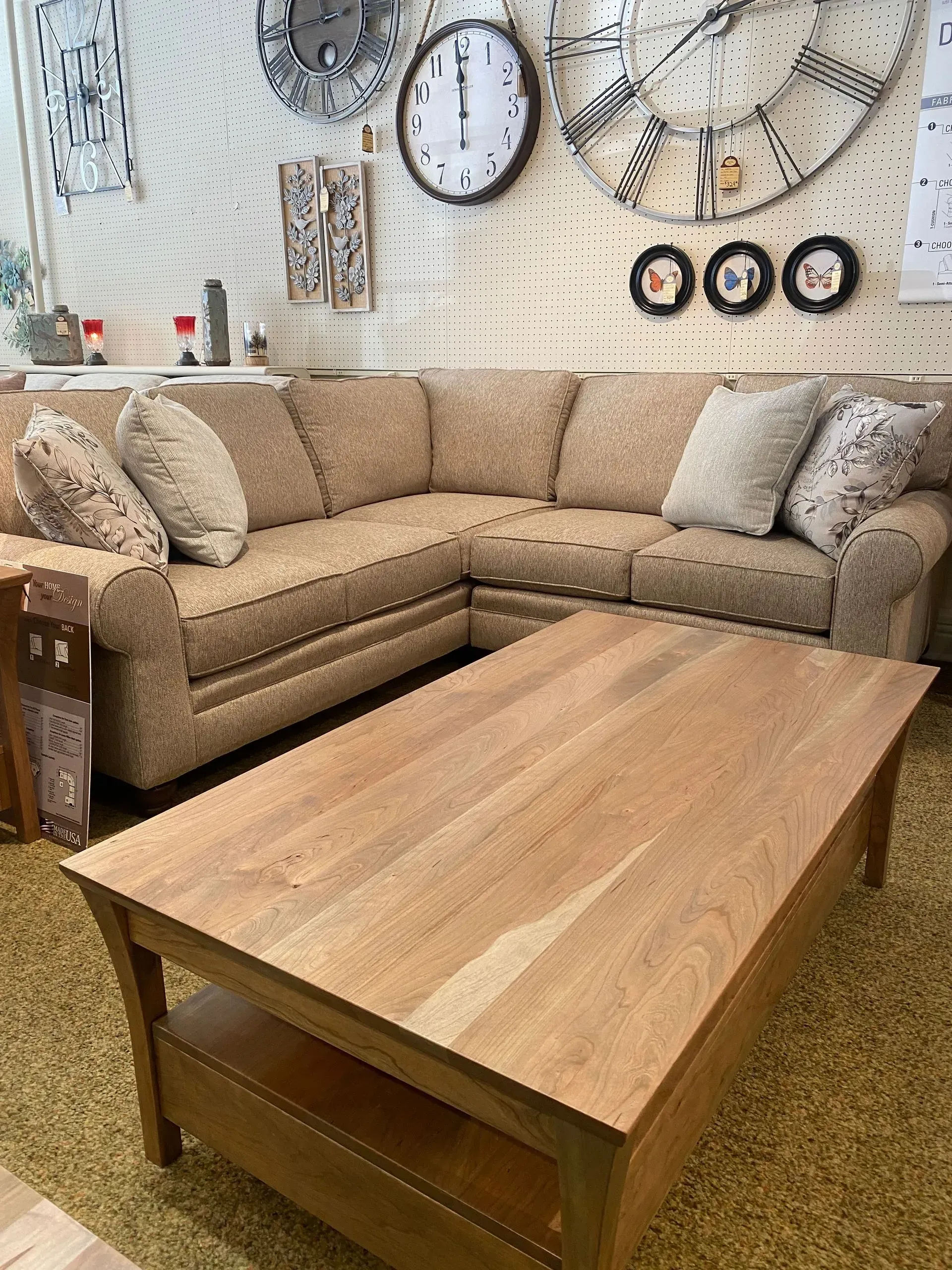 Beige sectional sofa and wooden coffee table in a room with clocks on the wall.