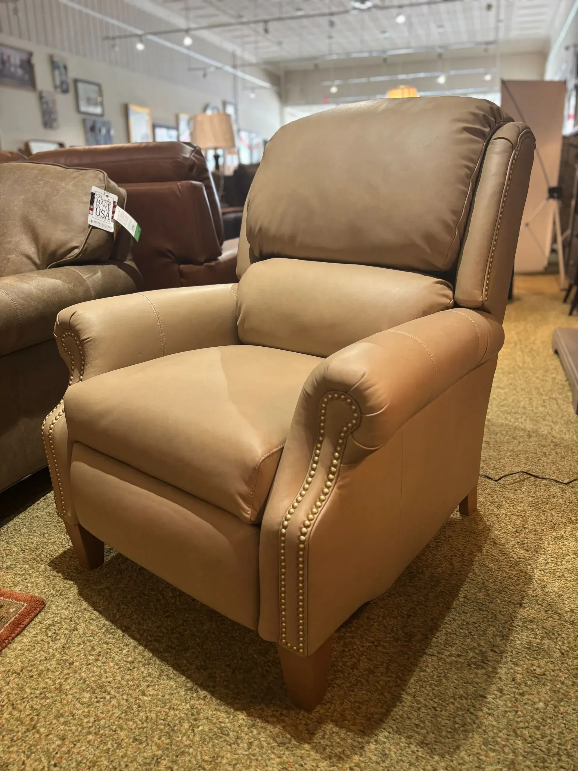 Tan leather recliner chair in a showroom setting.