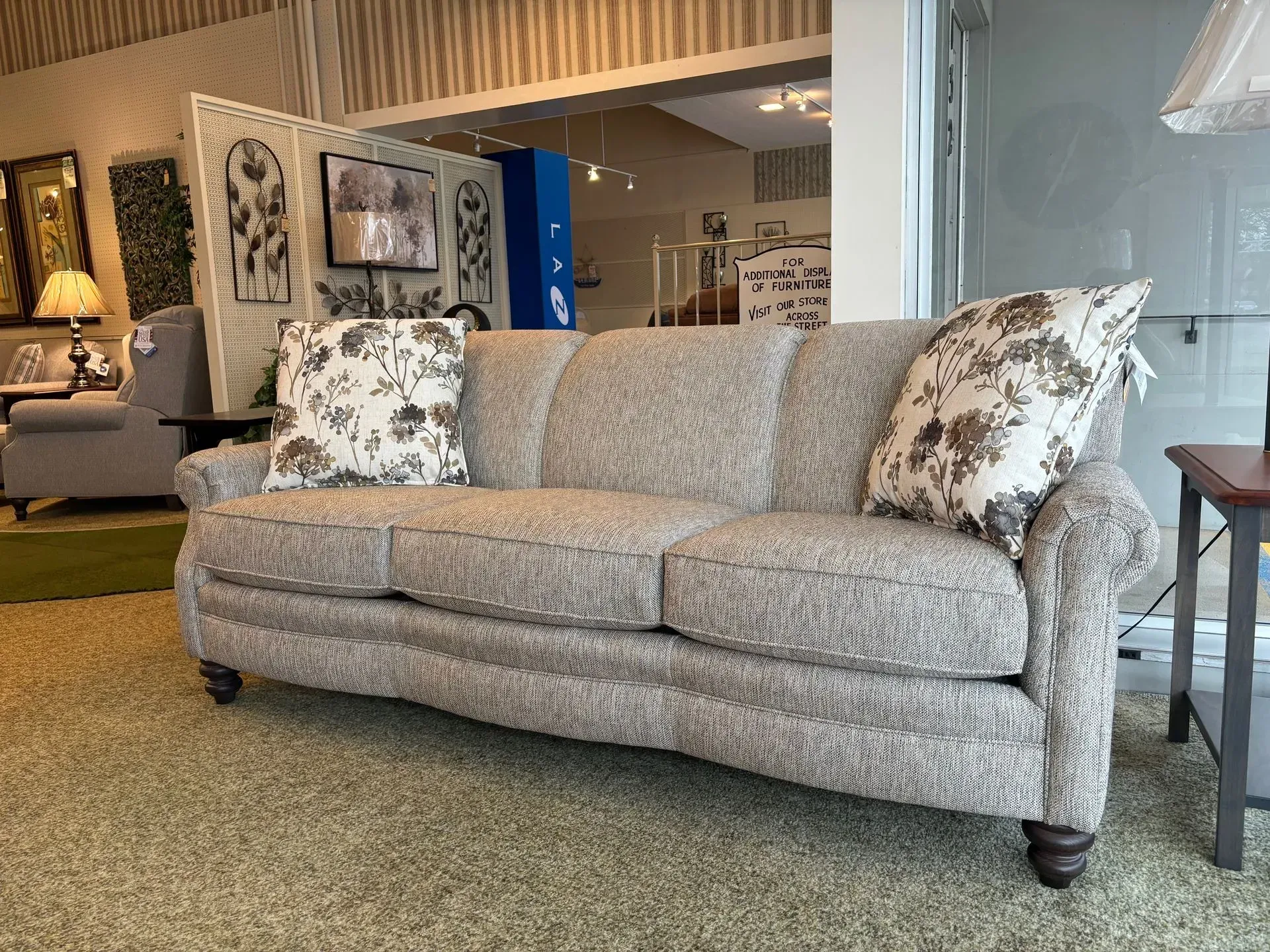 Beige sofa with floral pillows in a furniture store.