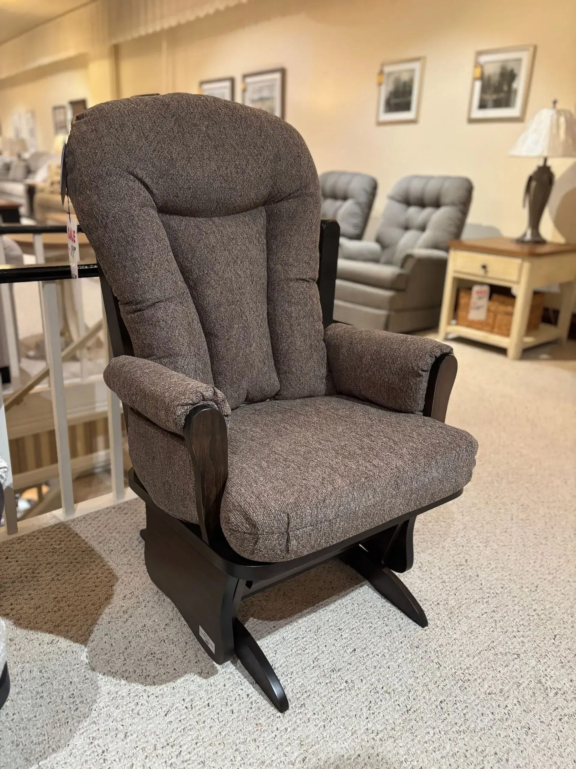 Brown upholstered glider chair in a furniture store.