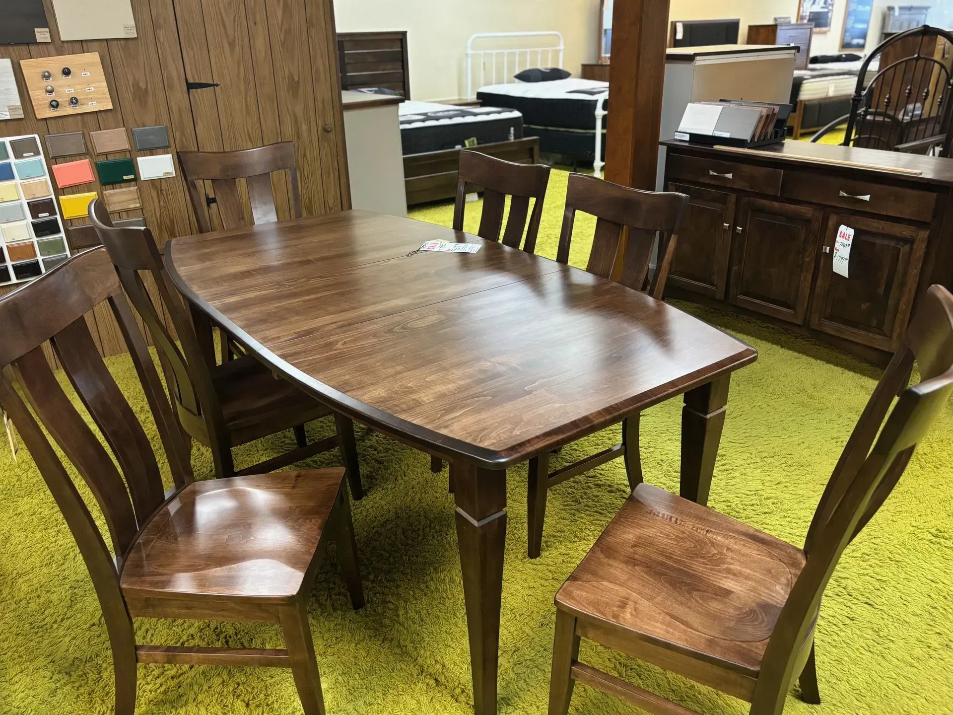 Wooden dining table with four chairs, in a furniture store setting.