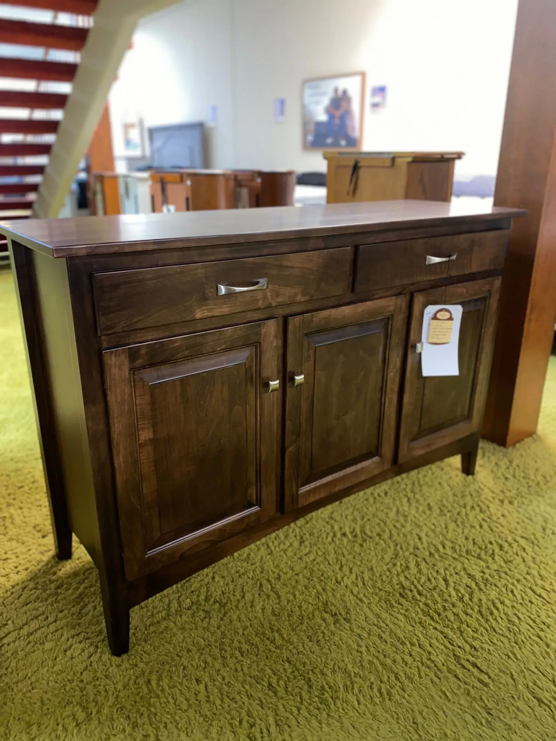 Wooden cabinet with drawers and doors, brown finish, on a green rug.