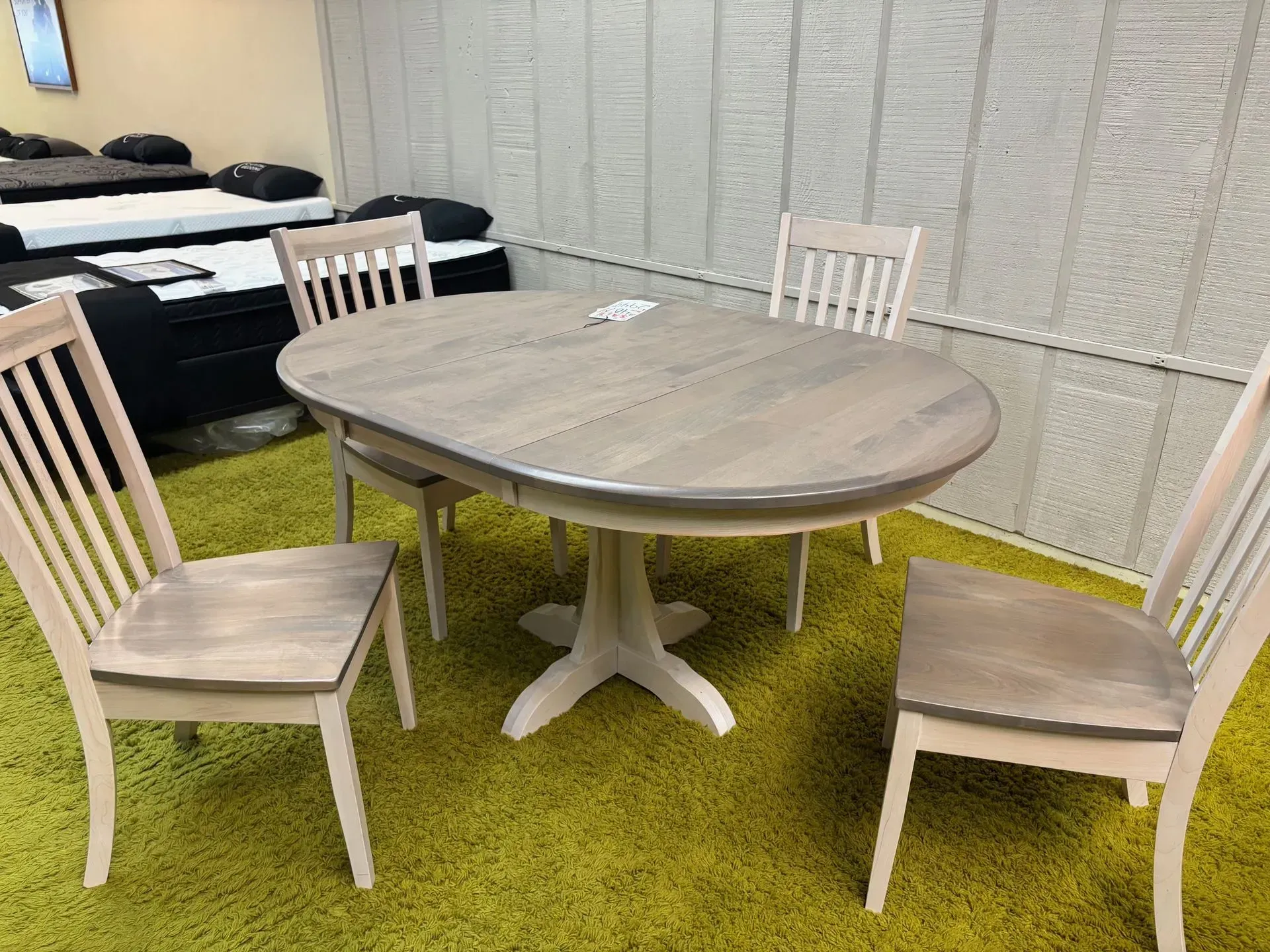 Dining table with four chairs on a yellow-green carpet. Table has a light wood finish.