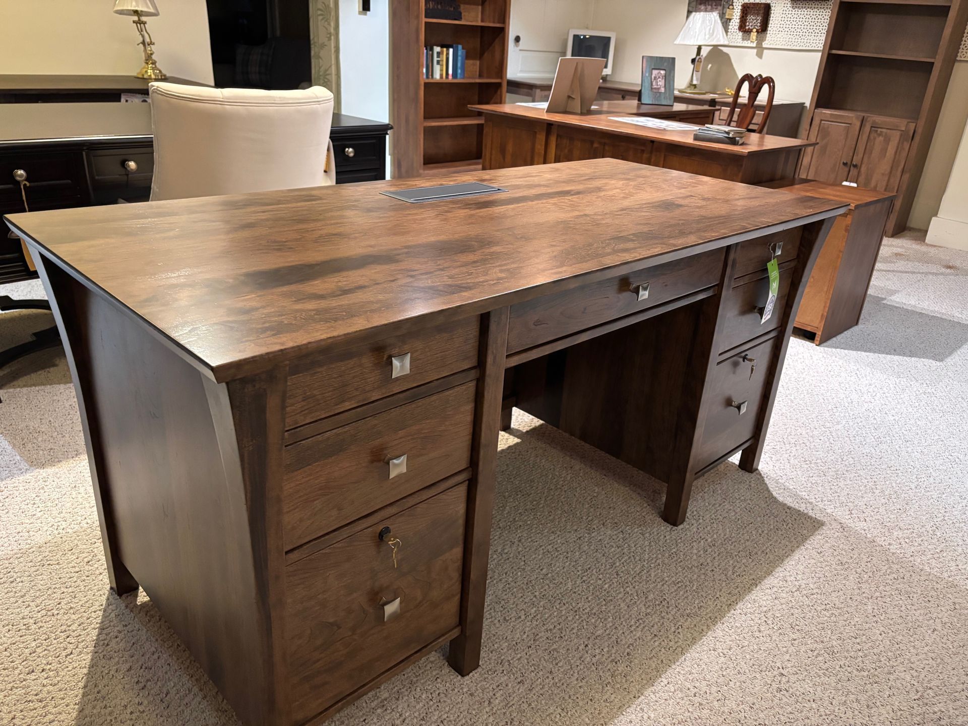 Wooden desk with multiple drawers, in a showroom setting.